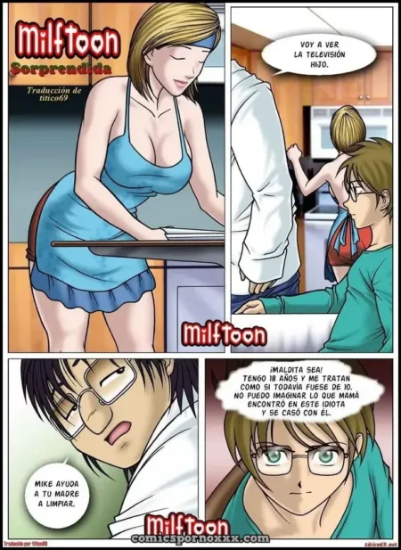 Mujer rubia con vestido corto azul y escote pronunciado inclinada en la cocina mientras un joven la observa.